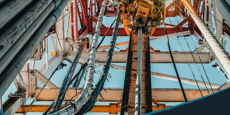 Marmon Keystone View looking up at steel pipes and equipment on an oil drilling rig, with text promoting Marmon/Keystone as your trusted metals distributor—with DOM tube and pipe in stock and ready to ship for oilfield supply chain needs.